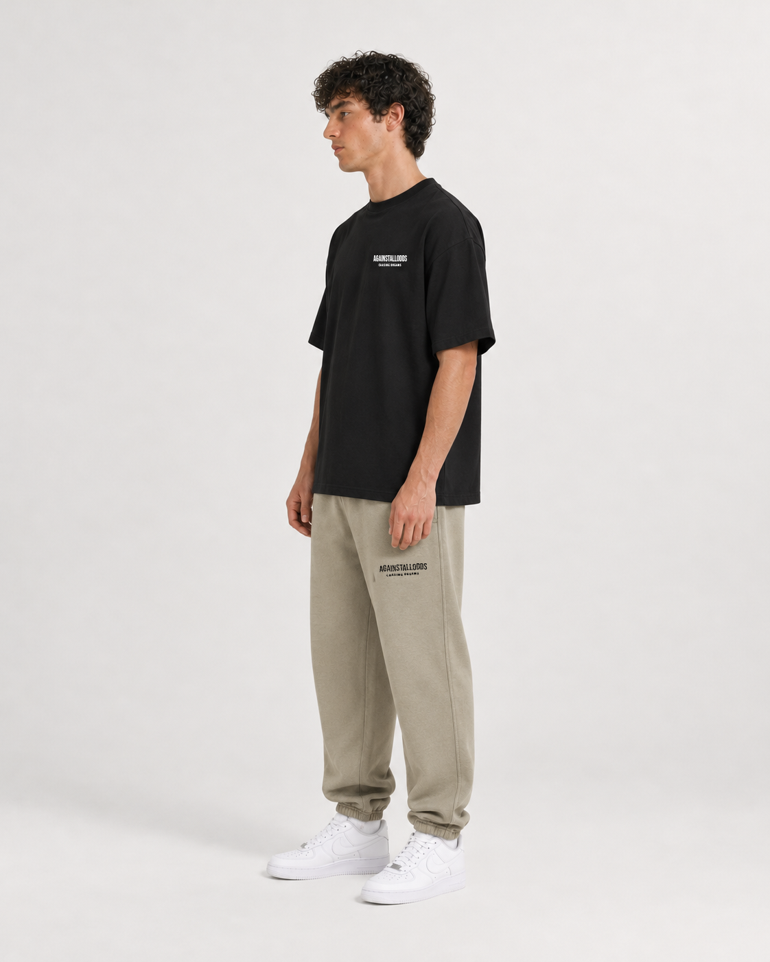 AI-generated styling illustration: Dreamers black luxury boxy tee with AAO Sandune sweatpants, three quarter view.