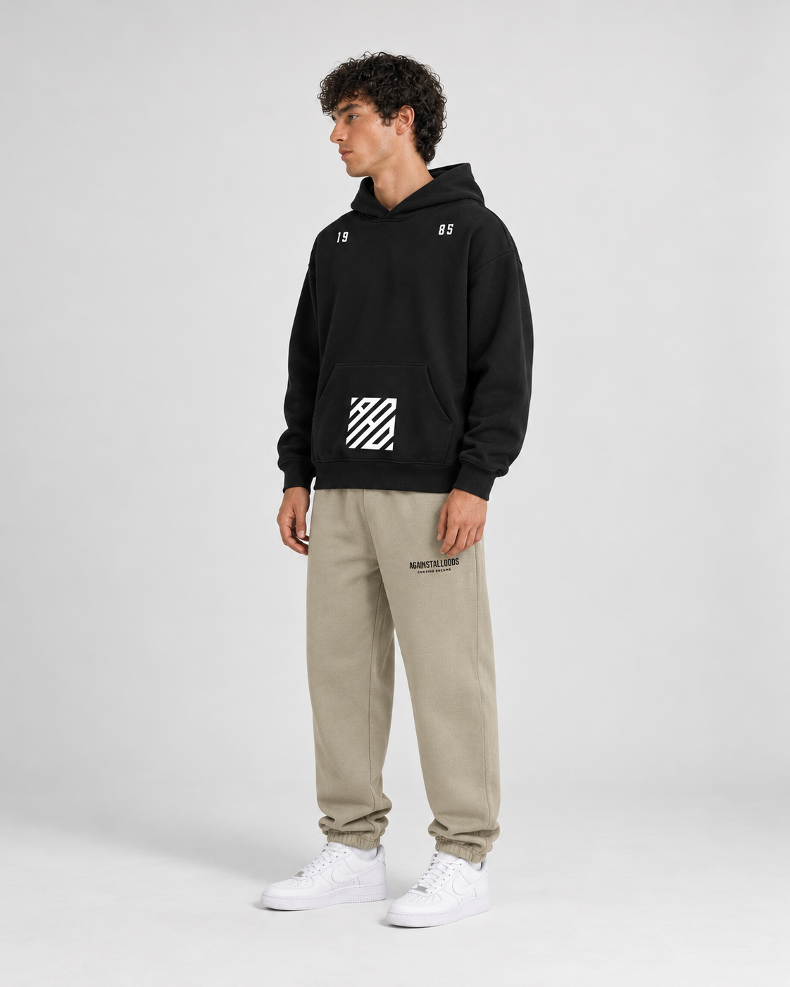 AI-generated styling illustration: AAO Tribute black hoodie with AAO Sandune sweatpants, side view.