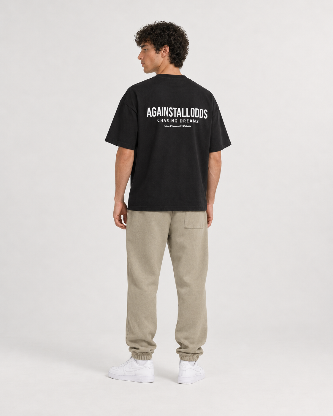 AI-generated styling illustration: Dreamers black luxury boxy tee with AAO Sandune sweatpants, back view.